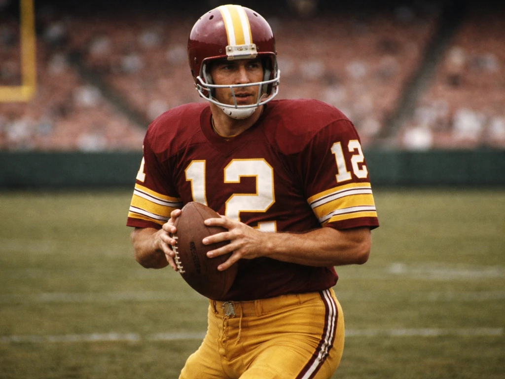 Vintage NFL quarterback in Washington Redskins colors standing on a stadium field, early football era feel.