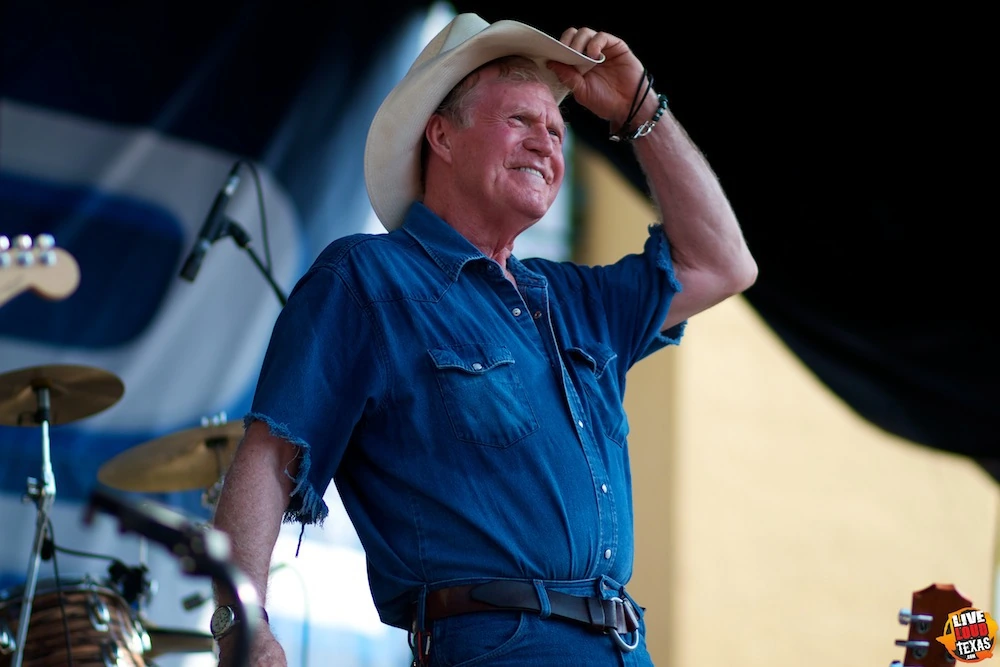 Billy Joe Shaver performing onstage in a cowboy hat and blue shirt