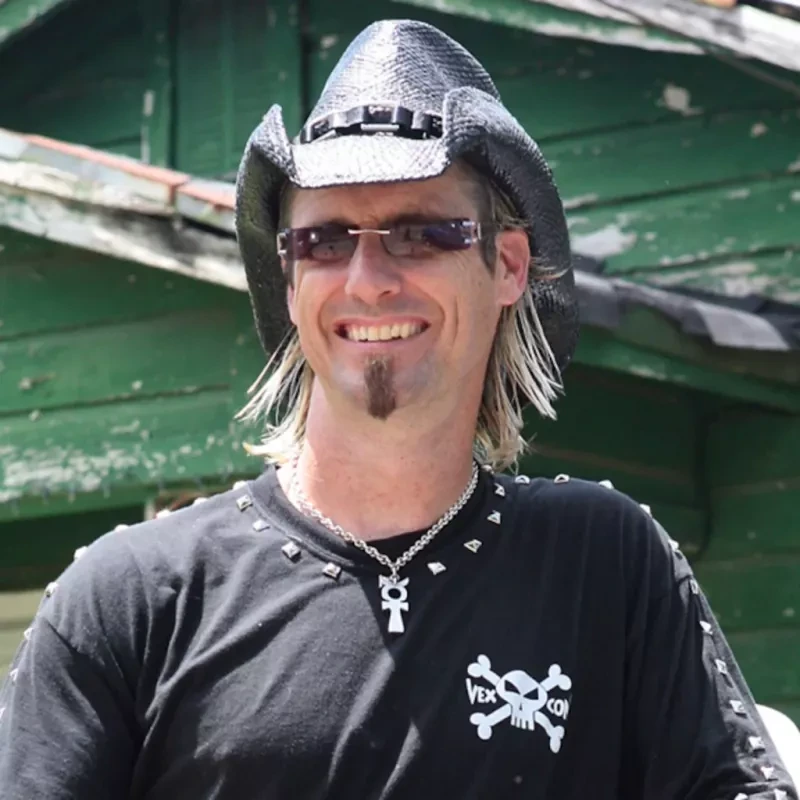 Billy Bretherton smiling outdoors in a black Vexcon shirt and cowboy hat