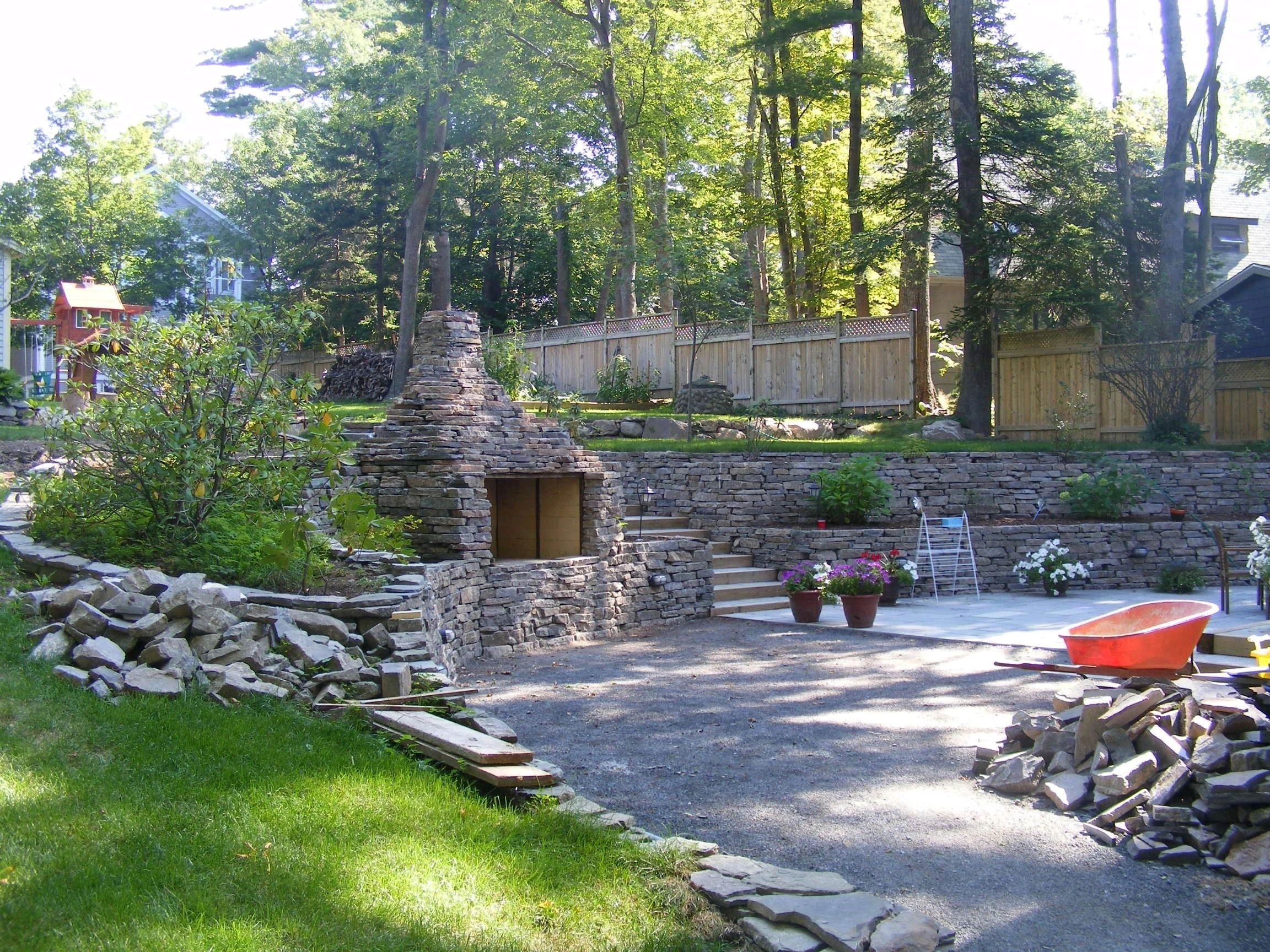 Landscape photo of a stone patio and retaining wall in a wooded yard
