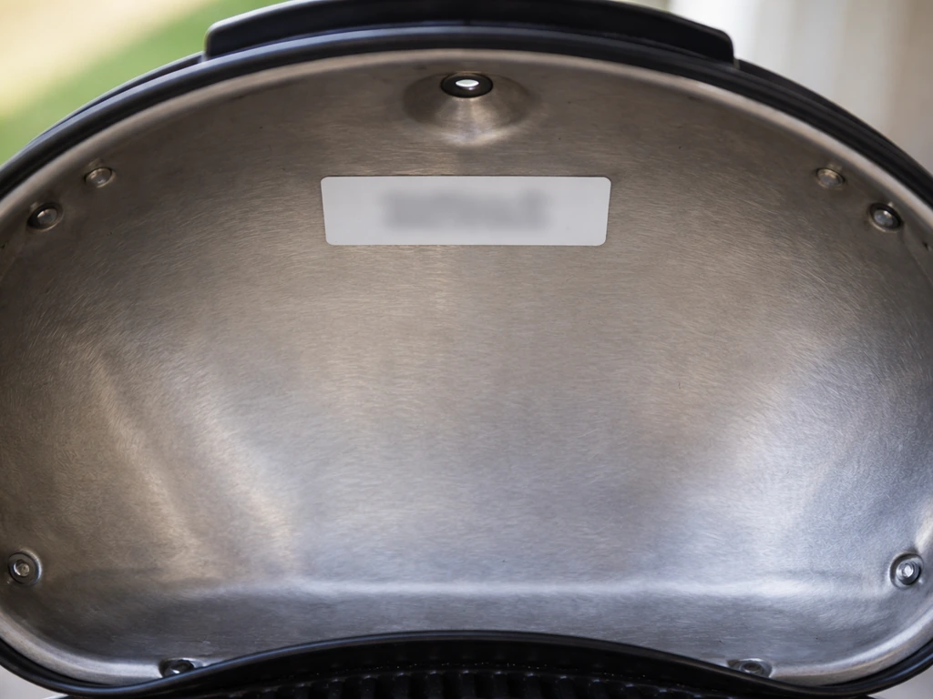 Close-up of the inside lid area with a blurred model number label on a Patio Bistro grill