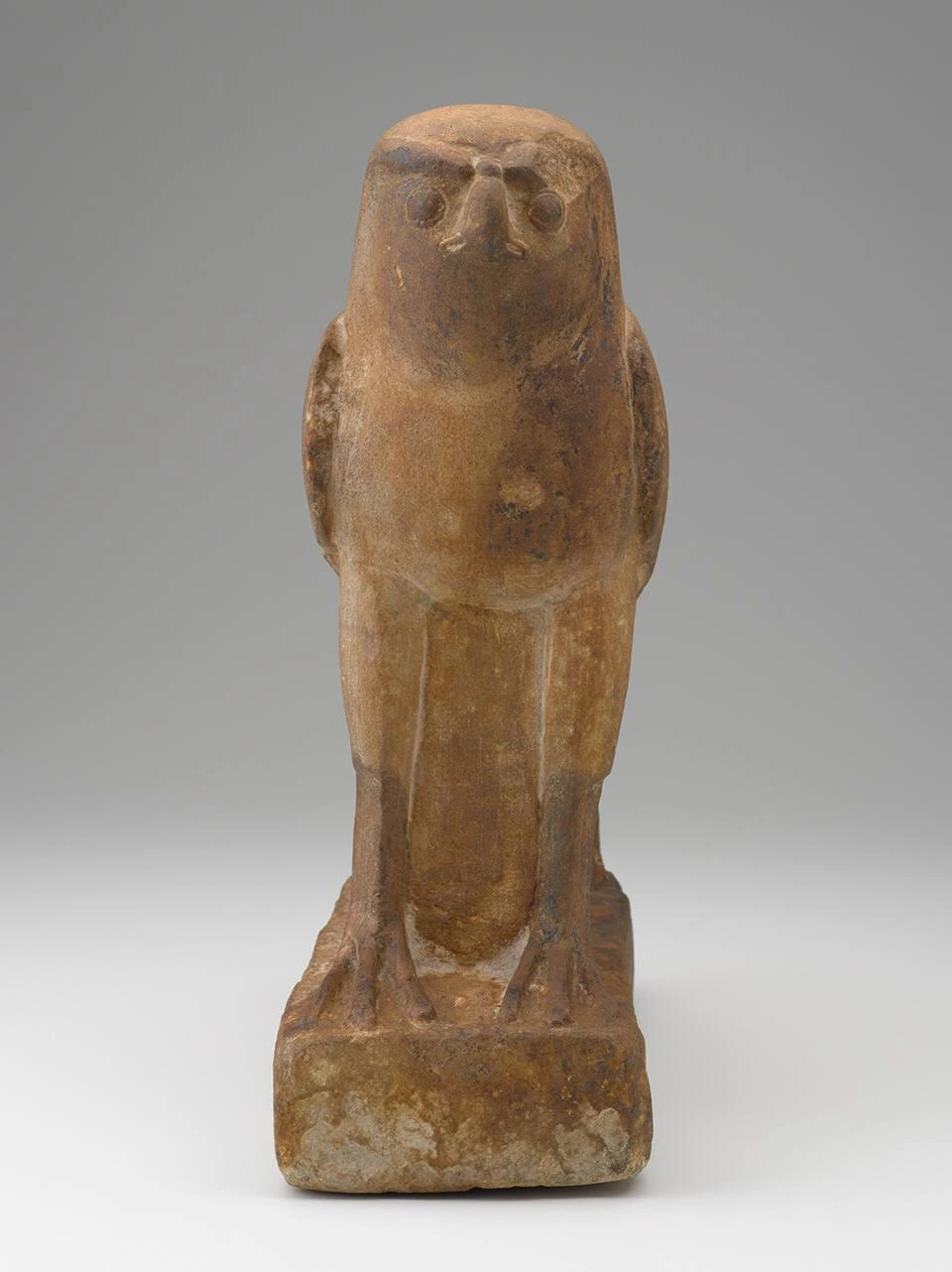 A museum photograph of an ancient Horus falcon figure standing upright against a neutral background.