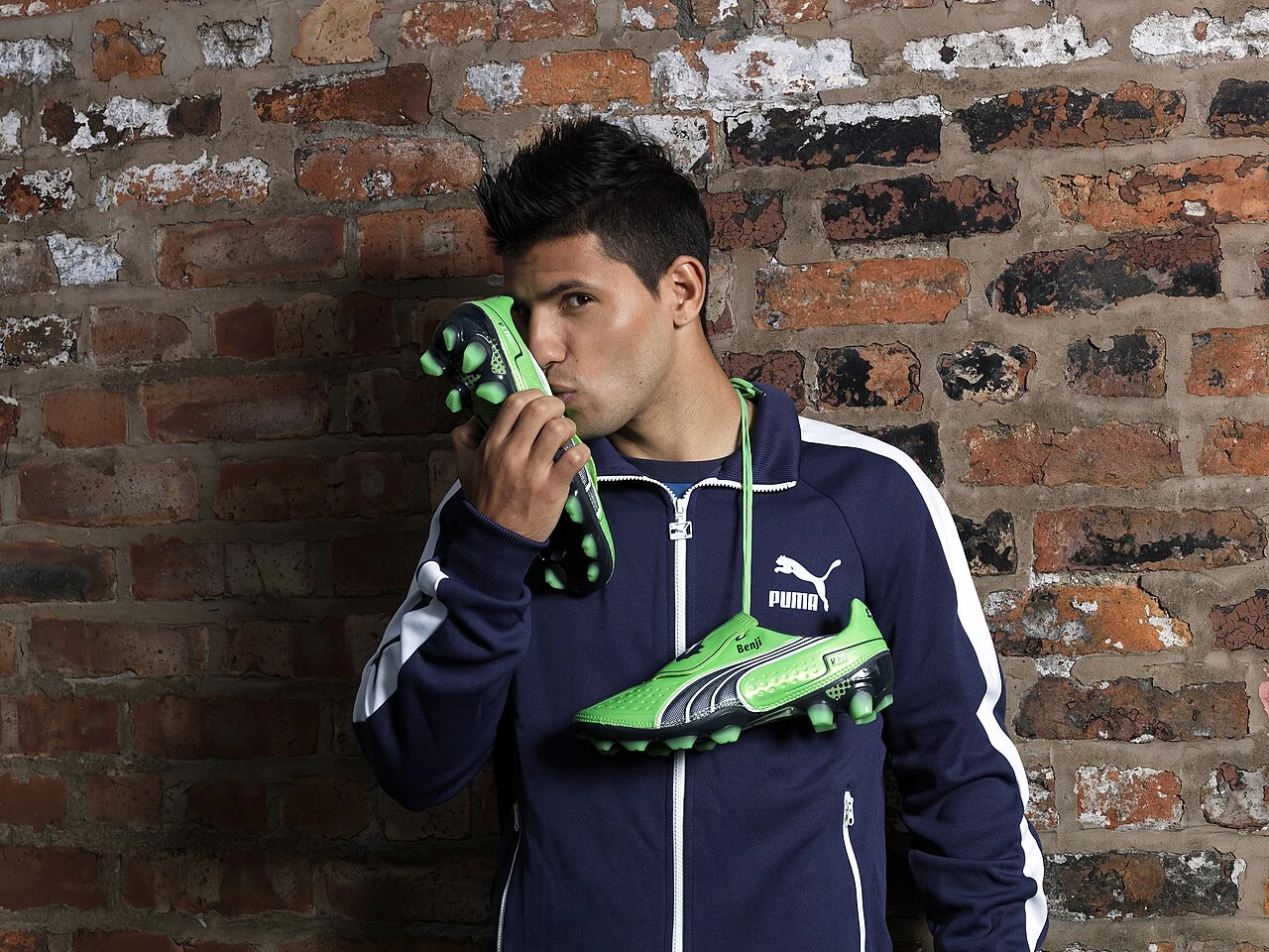 Sergio Agüero posing in a sportswear portrait against a brick wall