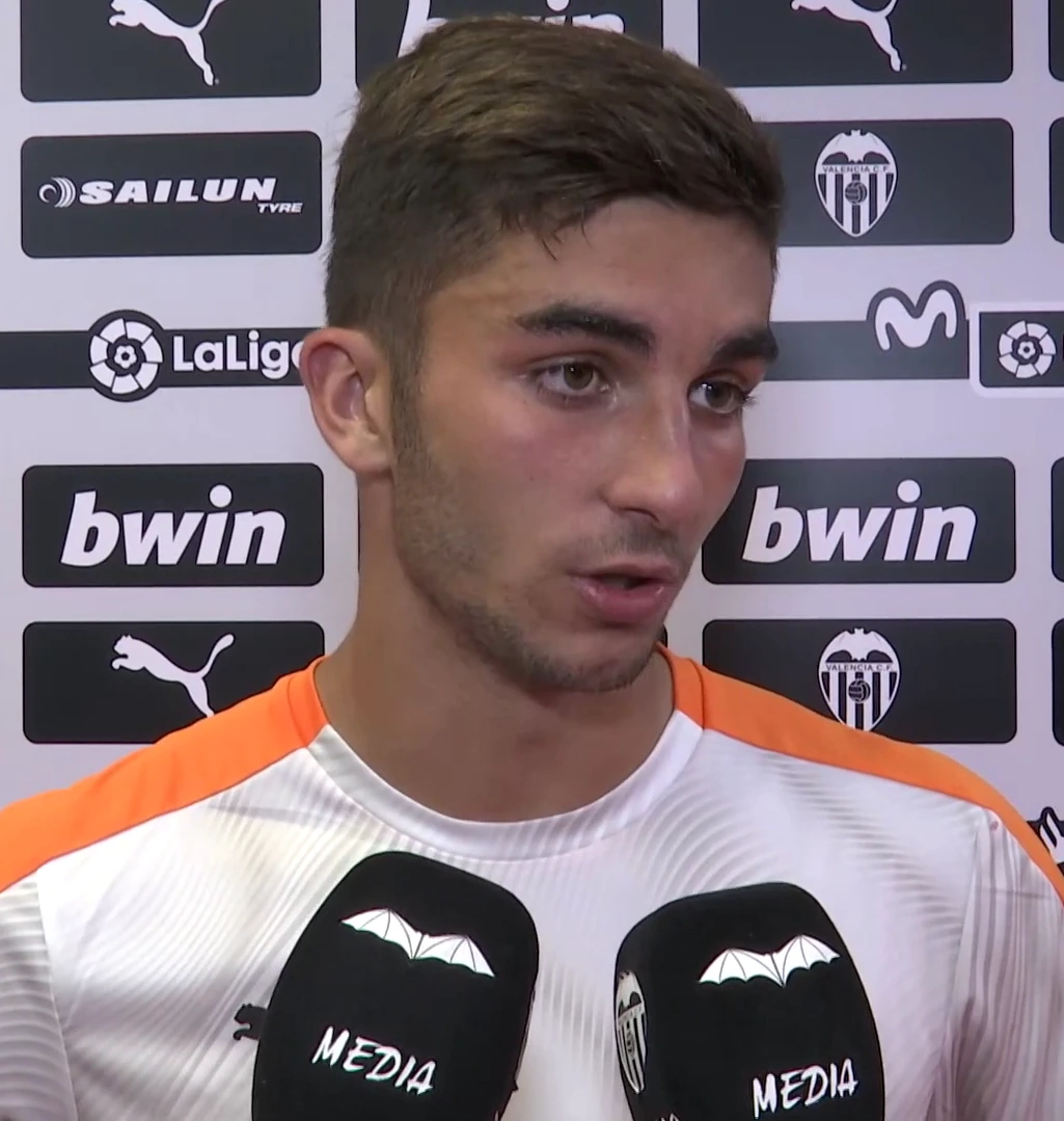 Ferran Torres speaking in front of a sponsor backdrop during a media interview