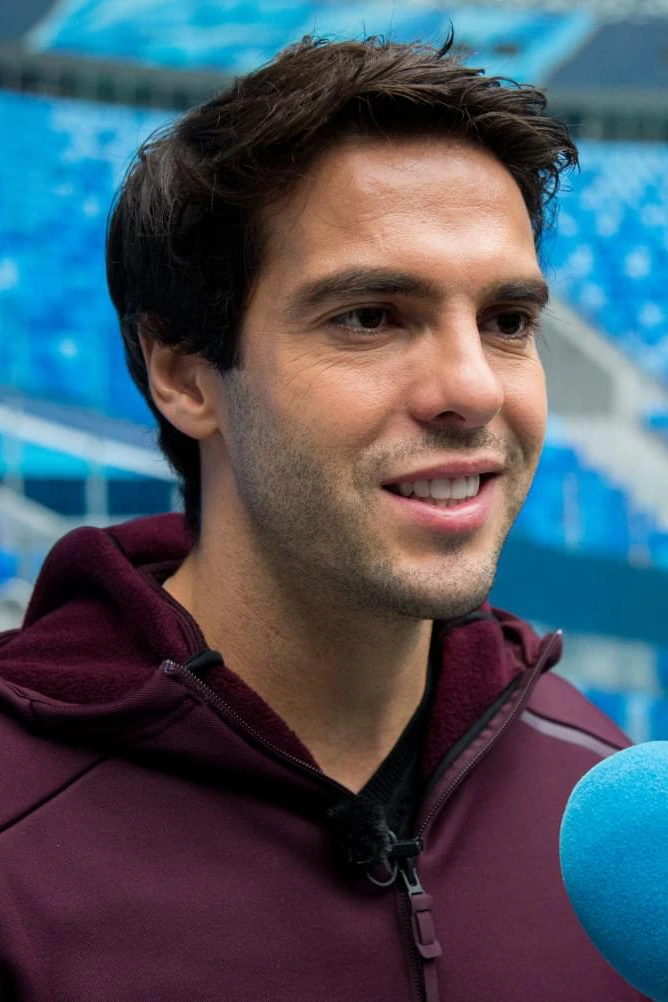 Kaká smiling in a maroon jacket at a stadium, close-up portrait photo