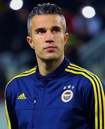 Robin van Persie in a blue Fenerbahçe training jacket, looking off-camera during a football match or warm-up setting.