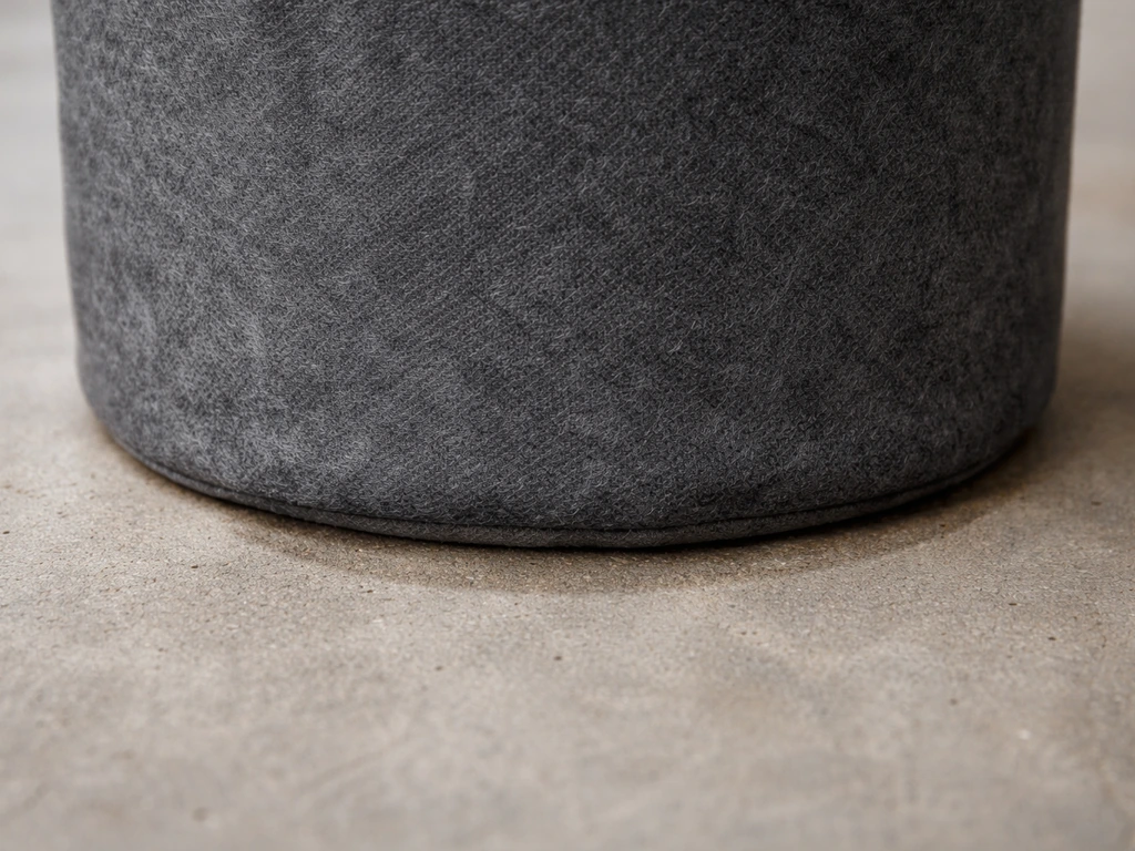 Fabric grow bag bottom pressed on bare concrete, showing contact and porous fabric texture.