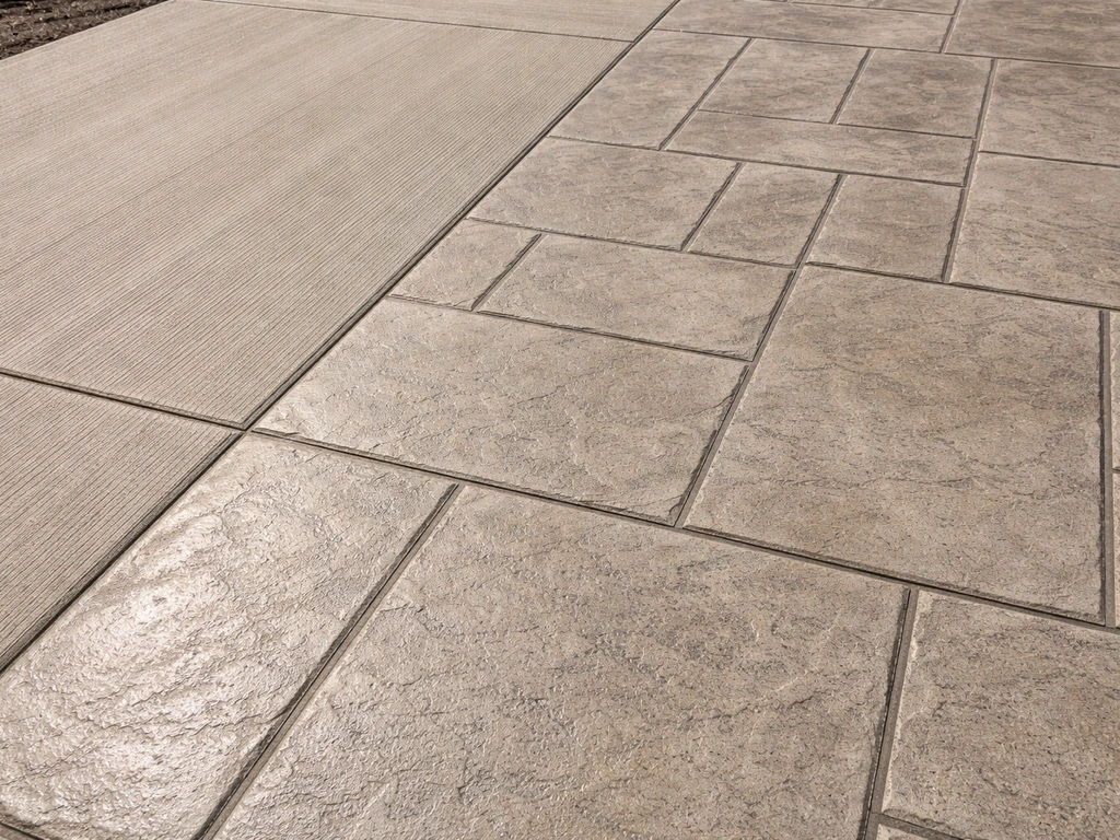 Close-up of a poured concrete patio slab showing broom texture and stamped-like surface pattern with joint lines