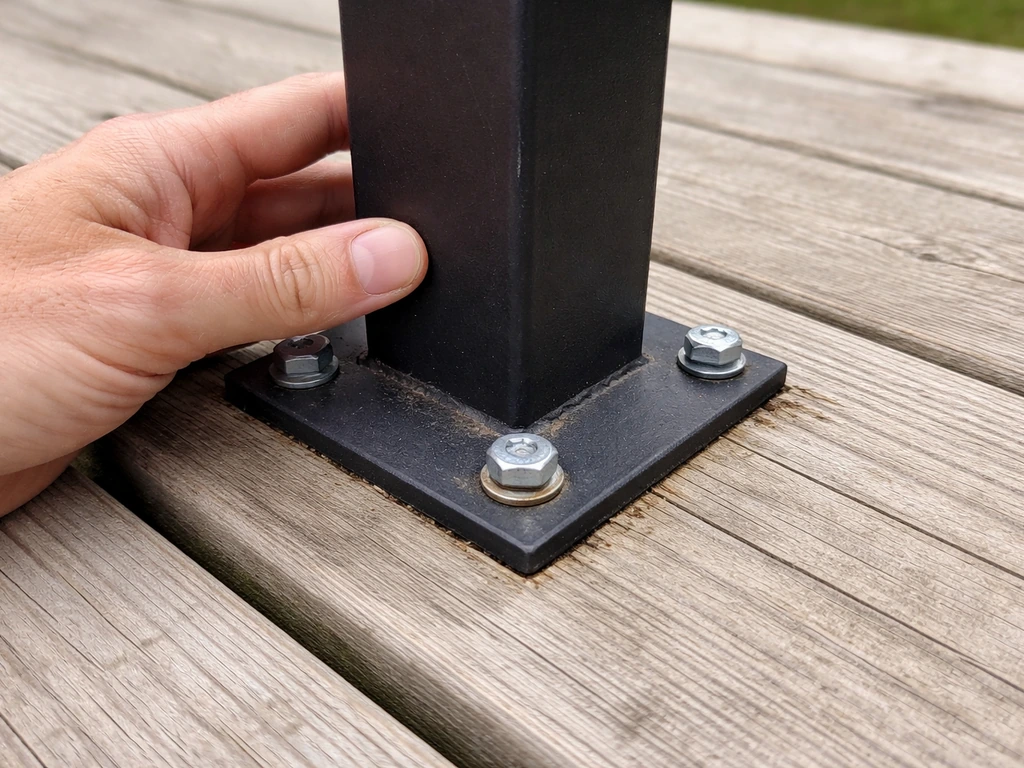 Close-up inspection of a loose railing post base on a deck, with fasteners being checked for play.