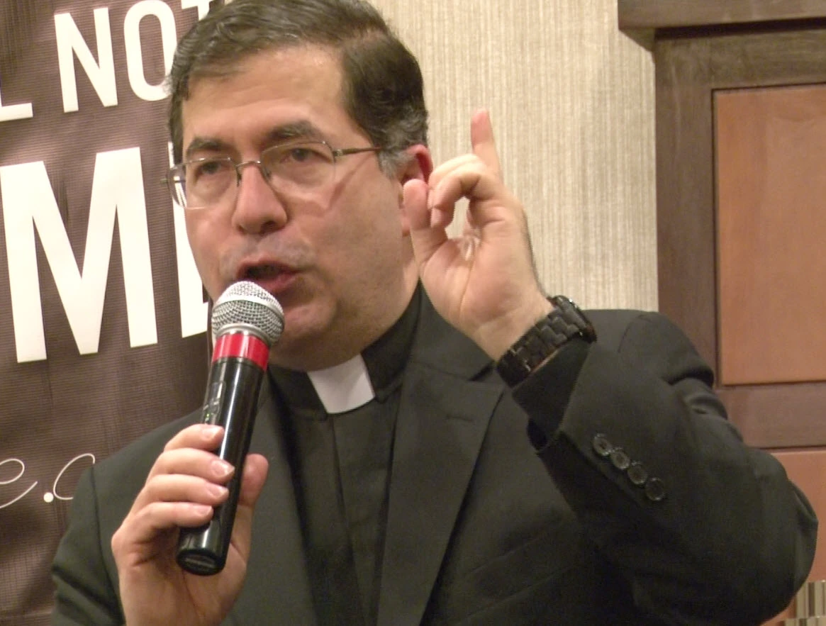 Frank Anthony Pavone speaking into a microphone and gesturing with his hand.