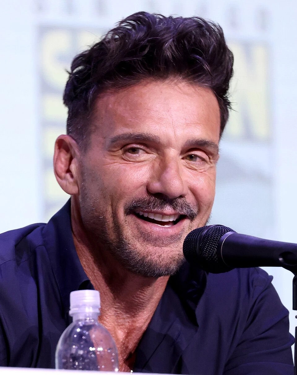 Frank Grillo speaking at a panel event, smiling beside a microphone