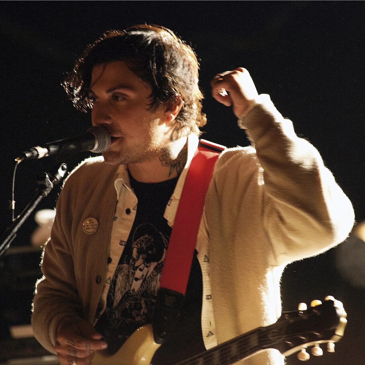Frank Iero performing on stage with a guitar and microphone