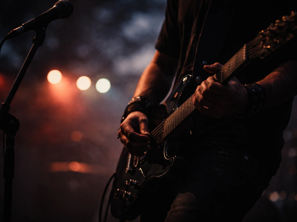 Close-up of anonymous hands playing an electric guitar on a dim concert stage with soft stage lights
