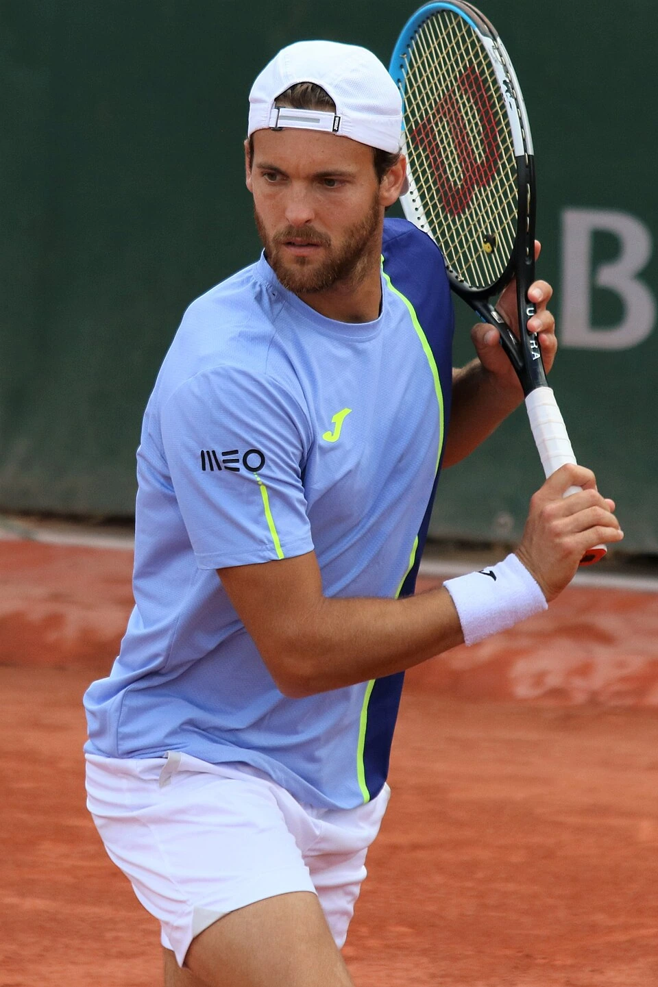 João Sousa preparing to return a shot on a clay tennis court
