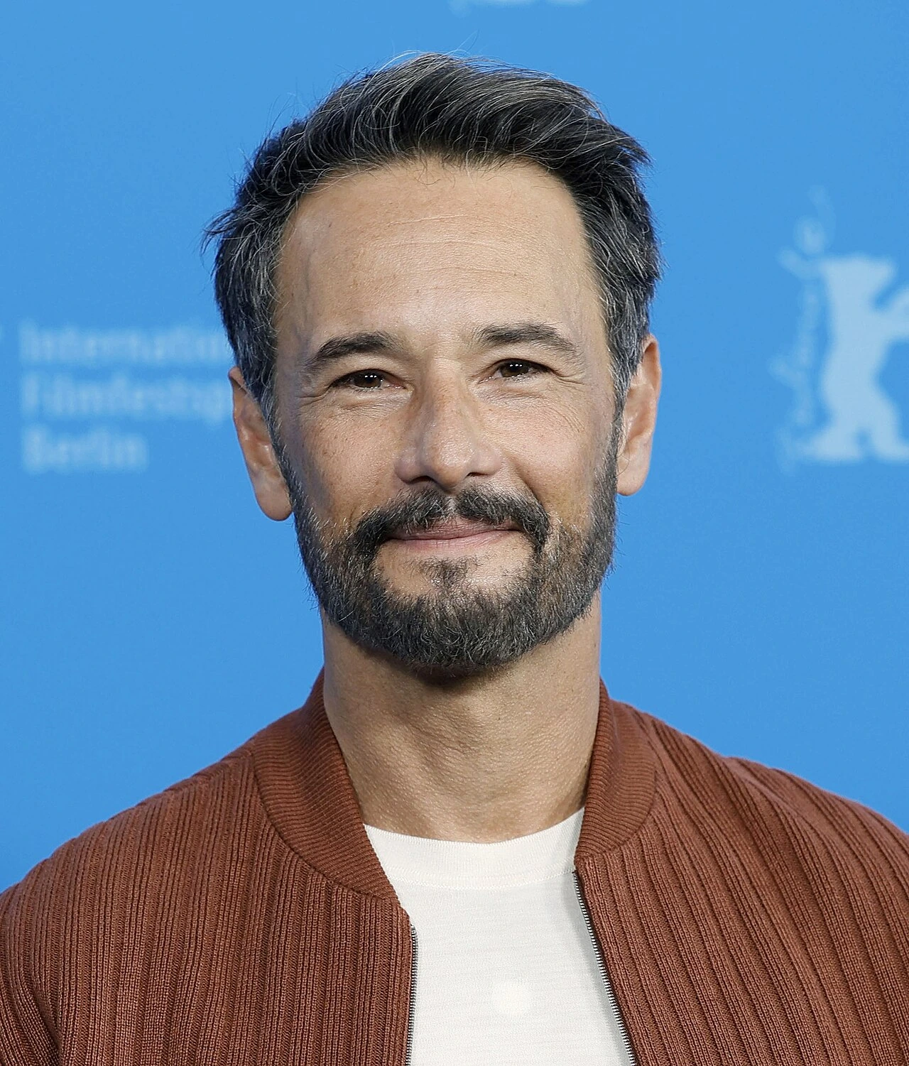 Rodrigo Santoro at the Berlinale 2025, posing against a blue backdrop