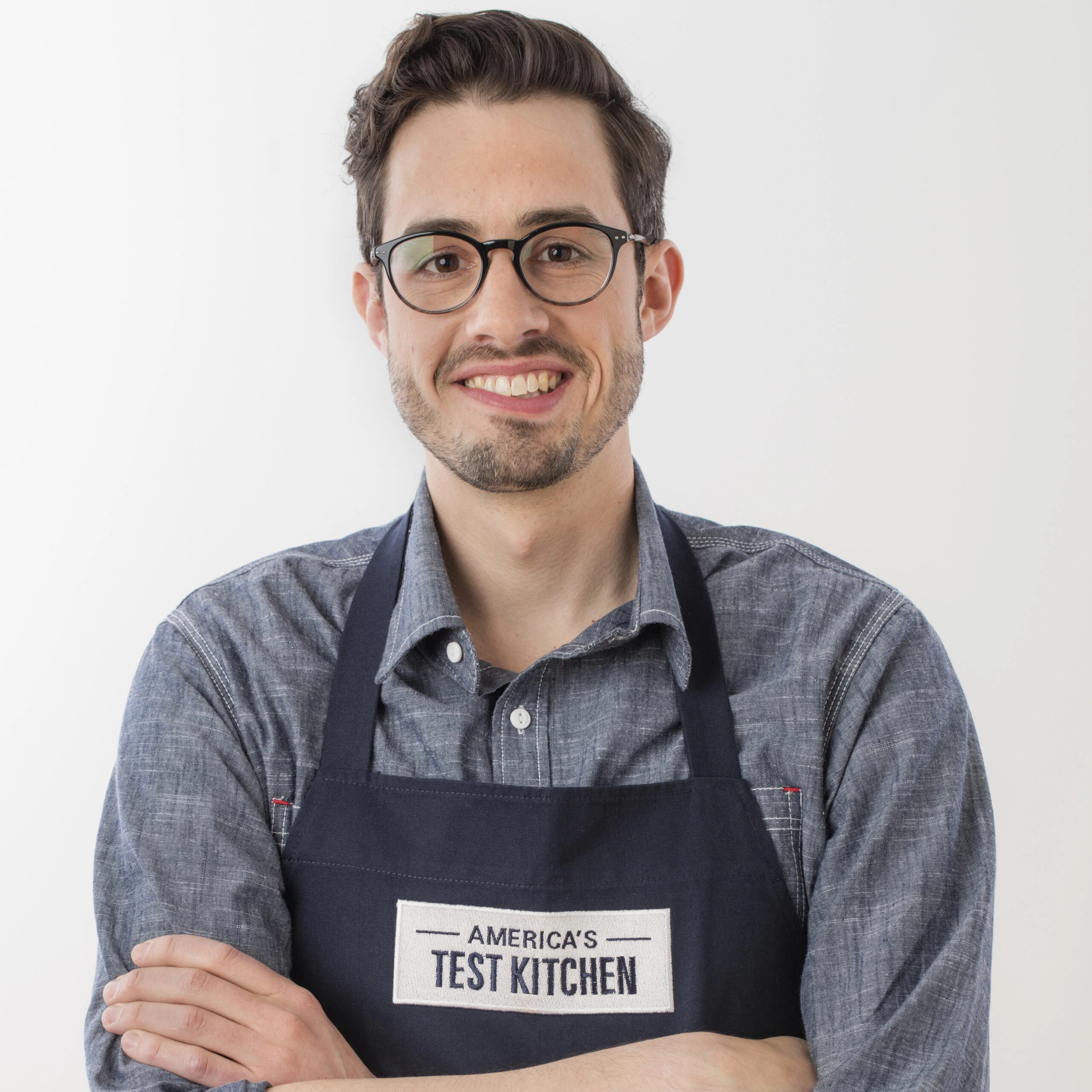 Portrait photo of Dan Souza wearing an America's Test Kitchen apron and smiling against a plain background.