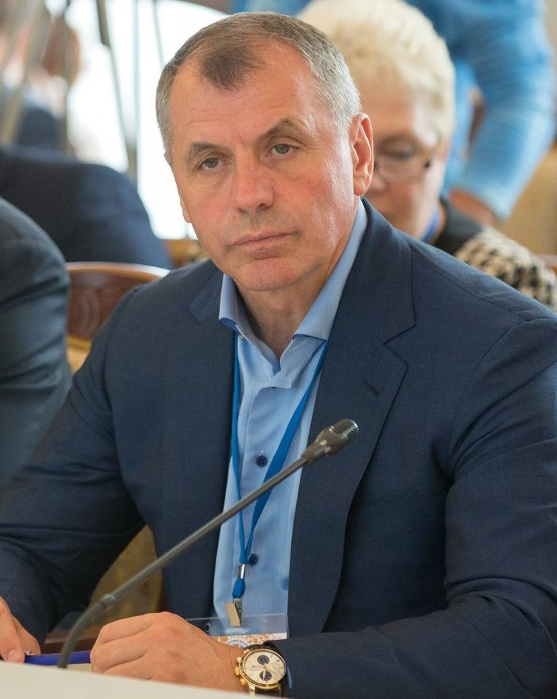 Vladimir Konstantinov seated at a meeting, wearing a dark suit and light blue shirt.