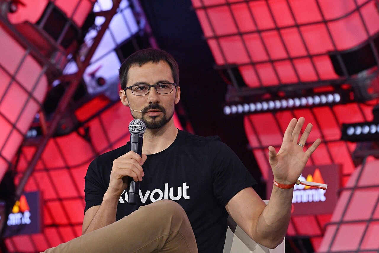 Vlad Yatsenko speaking on stage at a Revolut event, holding a microphone and gesturing with his hand.