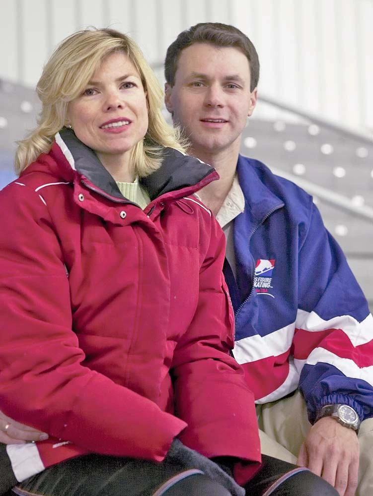 Vadim Naumov and Evgenia Shishkova sitting together at an ice rink, wearing winter jackets.