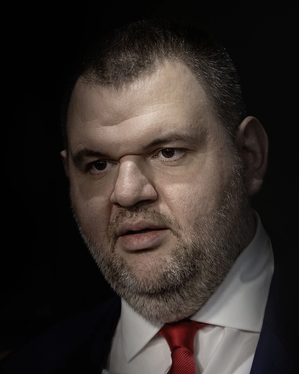 Portrait of Vasil Bozhkov in a dark studio setting wearing a suit and red tie.