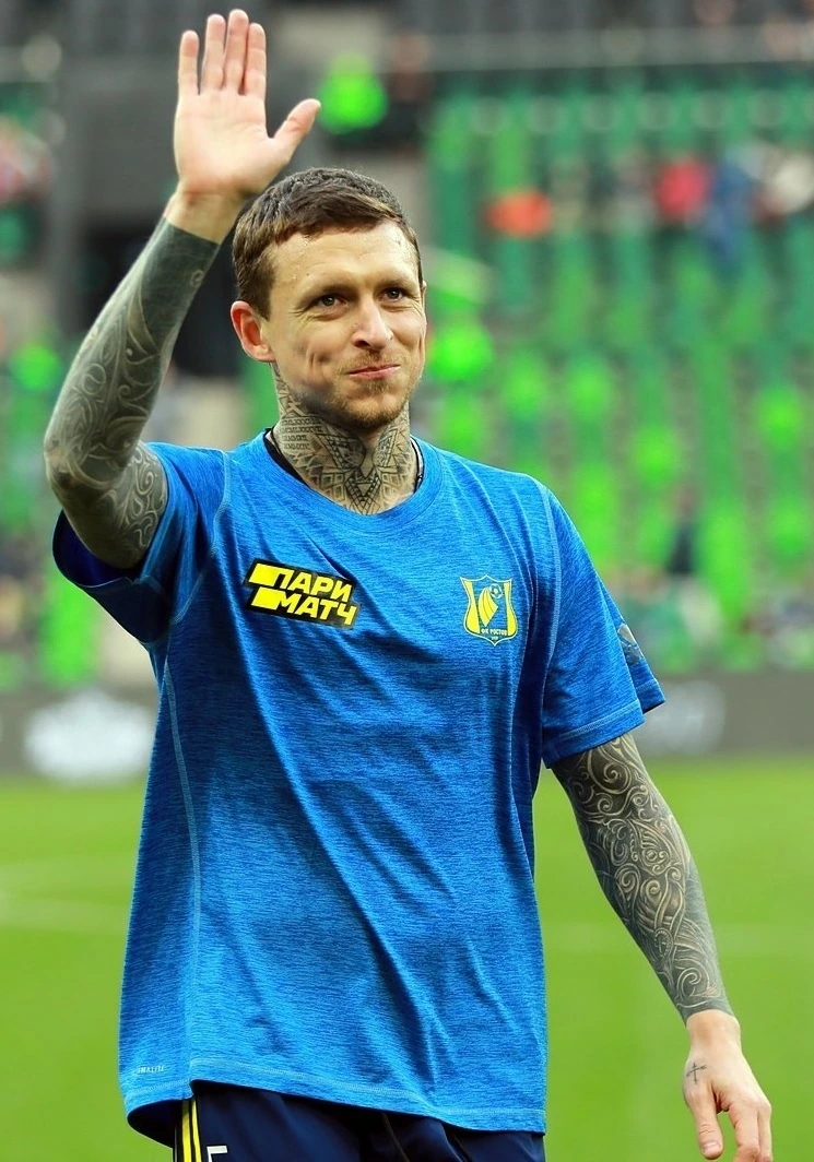 Pavel Mamaev waving on a football pitch in a blue training shirt