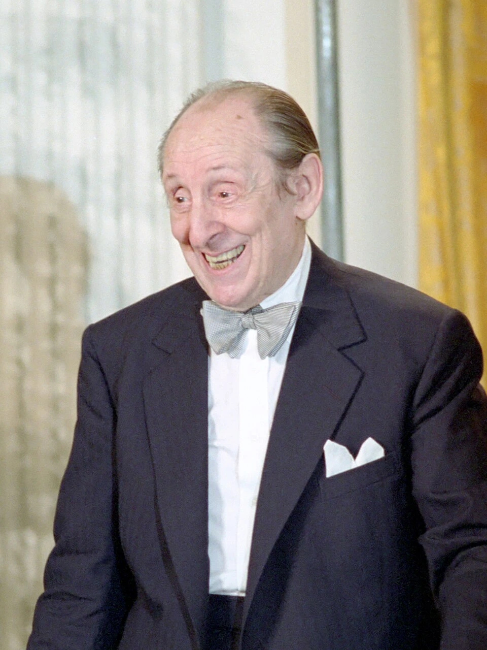Portrait photo of Vladimir Horowitz in a tuxedo, smiling during a formal event.