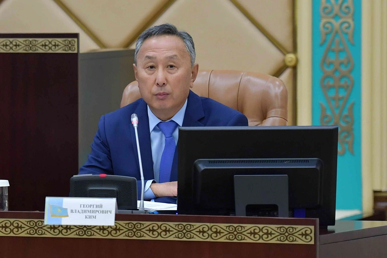 Portrait photo of Georgiy Vladimirovich Kim seated at a conference table in a suit and tie.