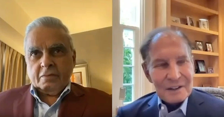 Video interview still showing Kiril Sokoloff in a split-screen conversation with another man in an indoor setting.