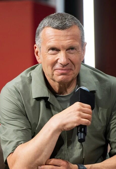 Portrait photo of Vladimir Solovyov, the Russian TV presenter, holding a microphone on a studio set.