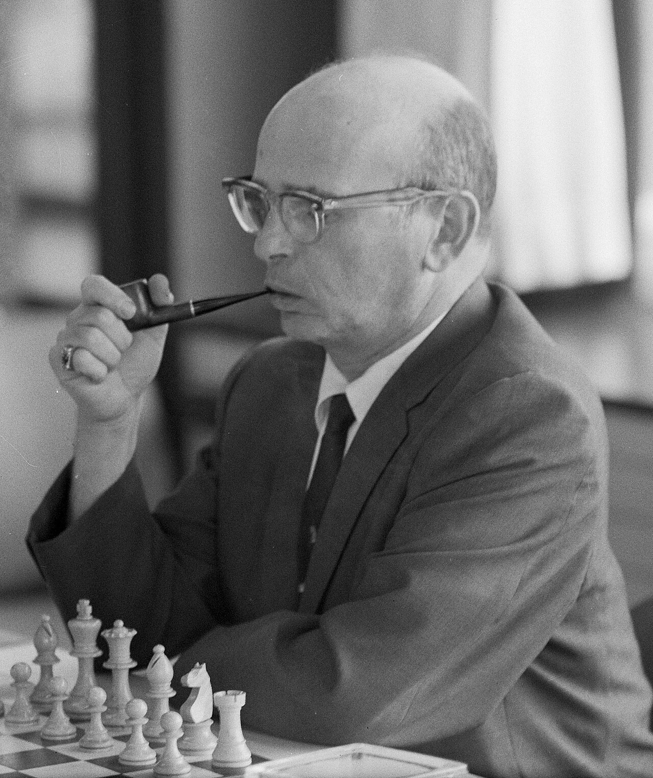 Samuel Reshevsky seated at a chessboard, holding a pipe and concentrating during play.
