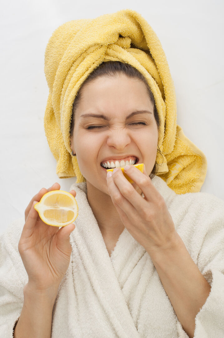 Junge Frau beißt in eine Zitrone