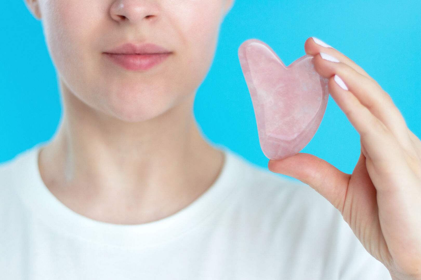 Frau hält Stein zur Gua-Sha Massage hoch