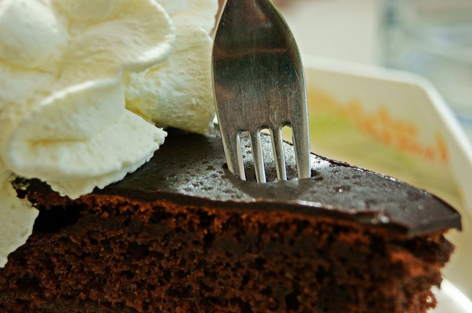 Eine Gabel sticht in eine Sacher-Torte mit Schlagobers