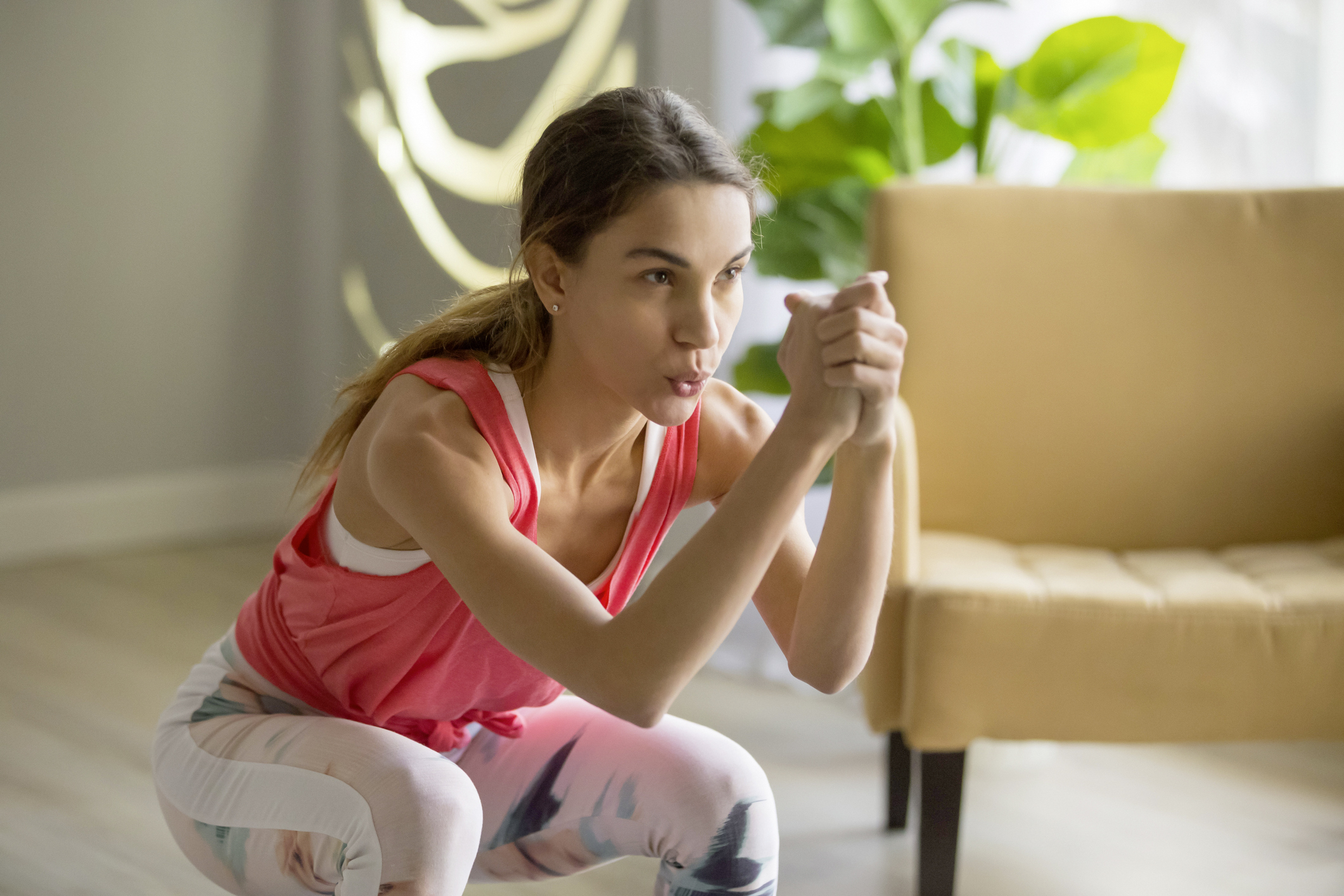 Junge Frau in Sportgewand beim Trainieren in ihrer Wohnung