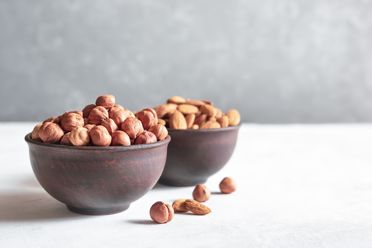 Schale mit geschälten Haselnüssen im Vordergrund, dahinter Schale mit Mandeln