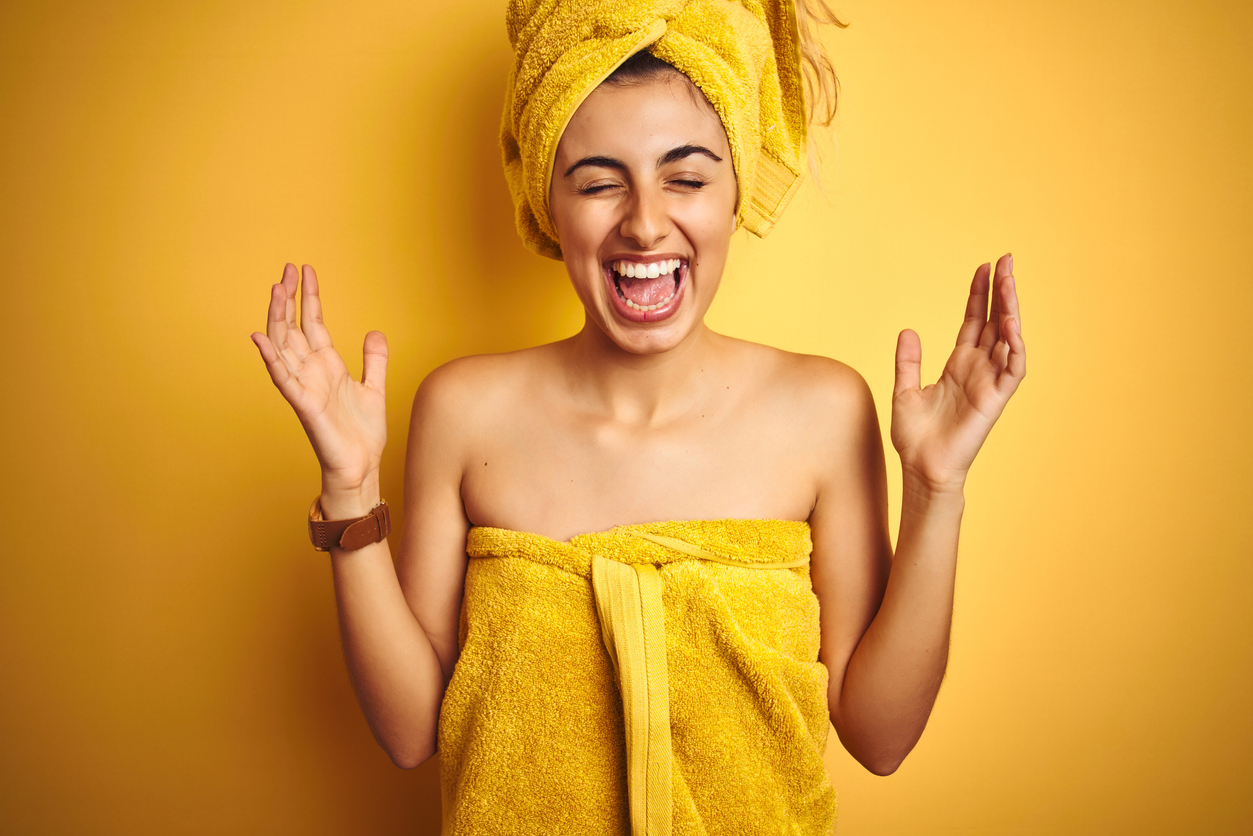 Eine lachende junge Frau mit Badehandtuch und Handtuchturban
