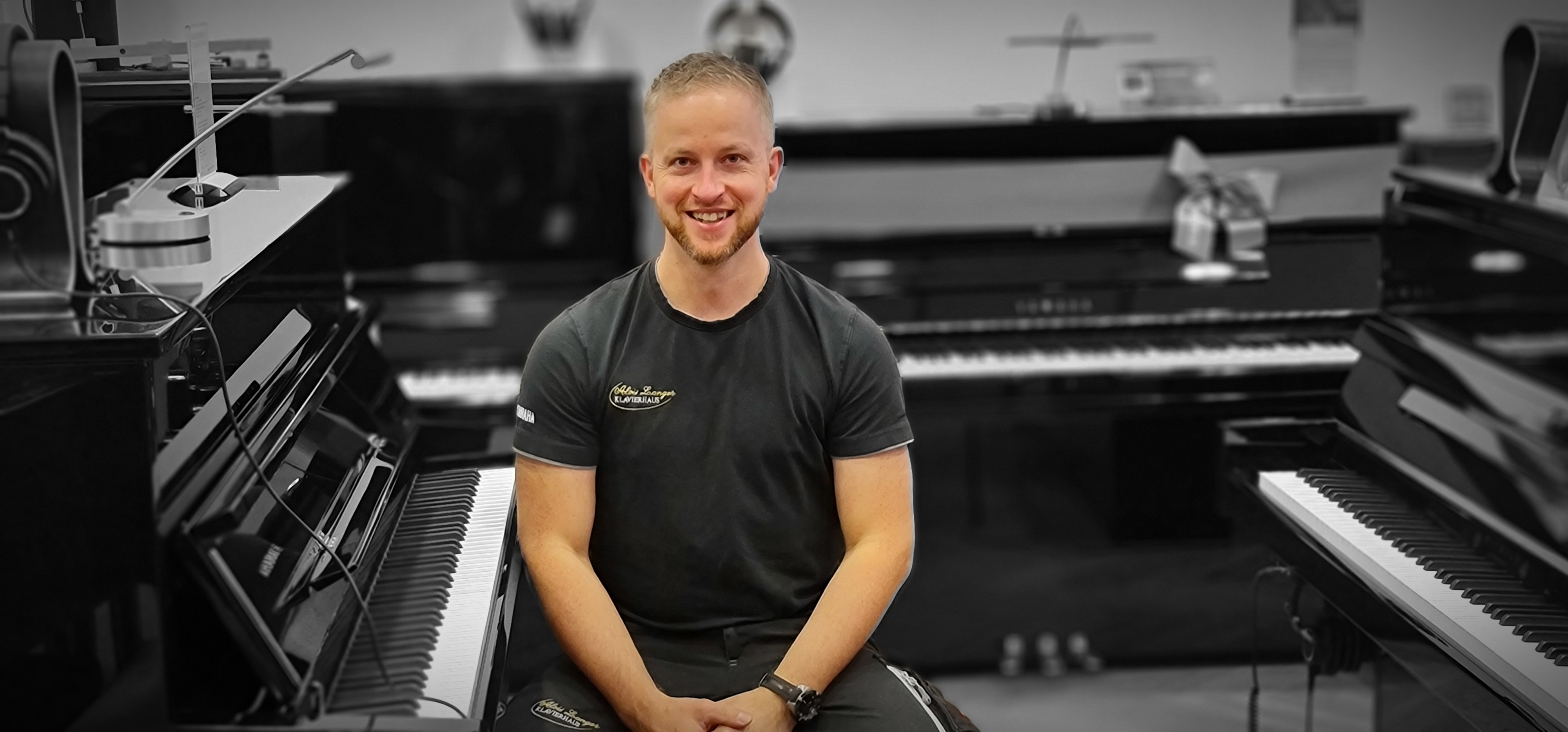 Alexander Langer sitzt neben einem Klavier