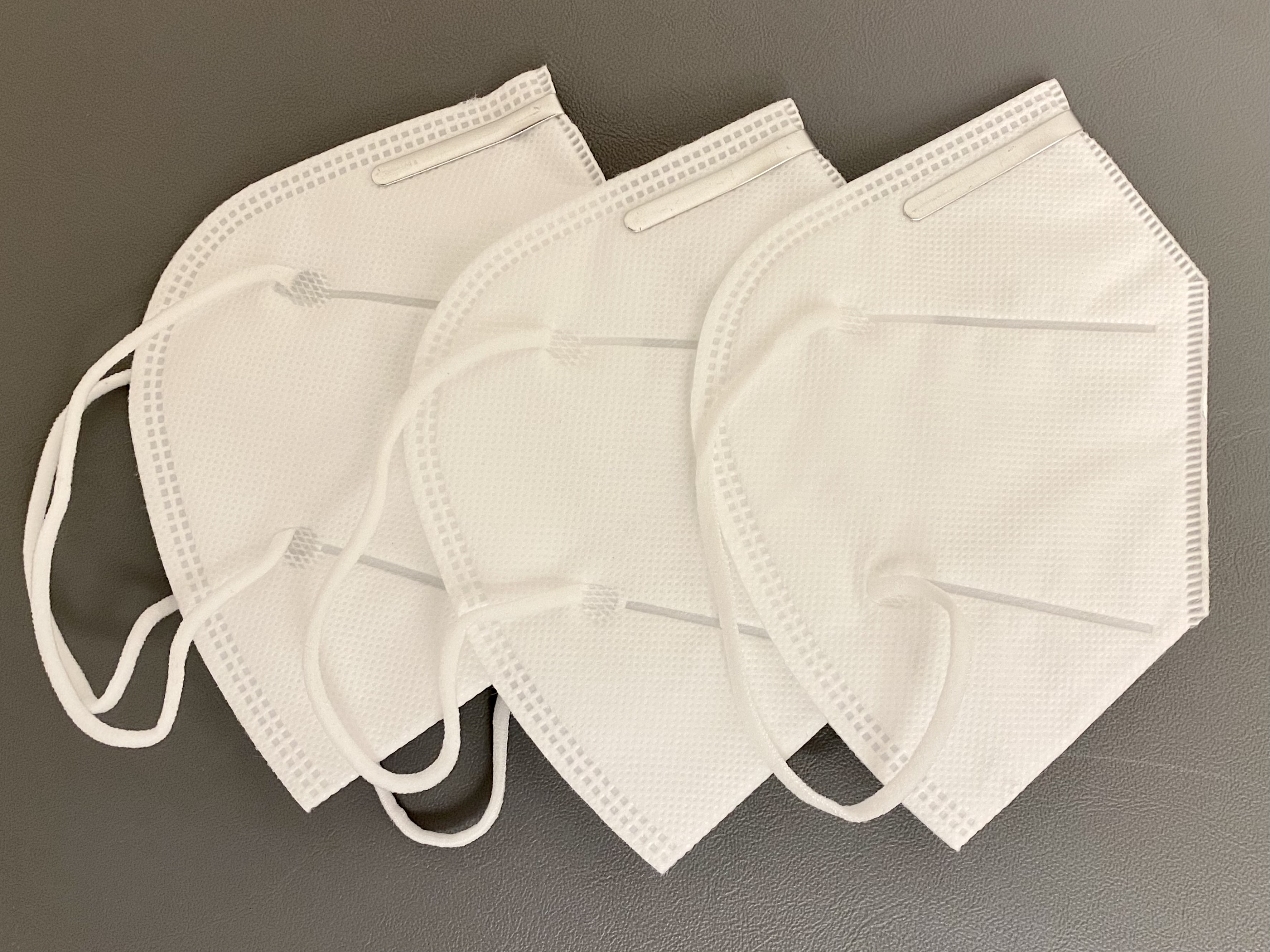 Drei FFP2-Masken auf einem neutralen Untergrund