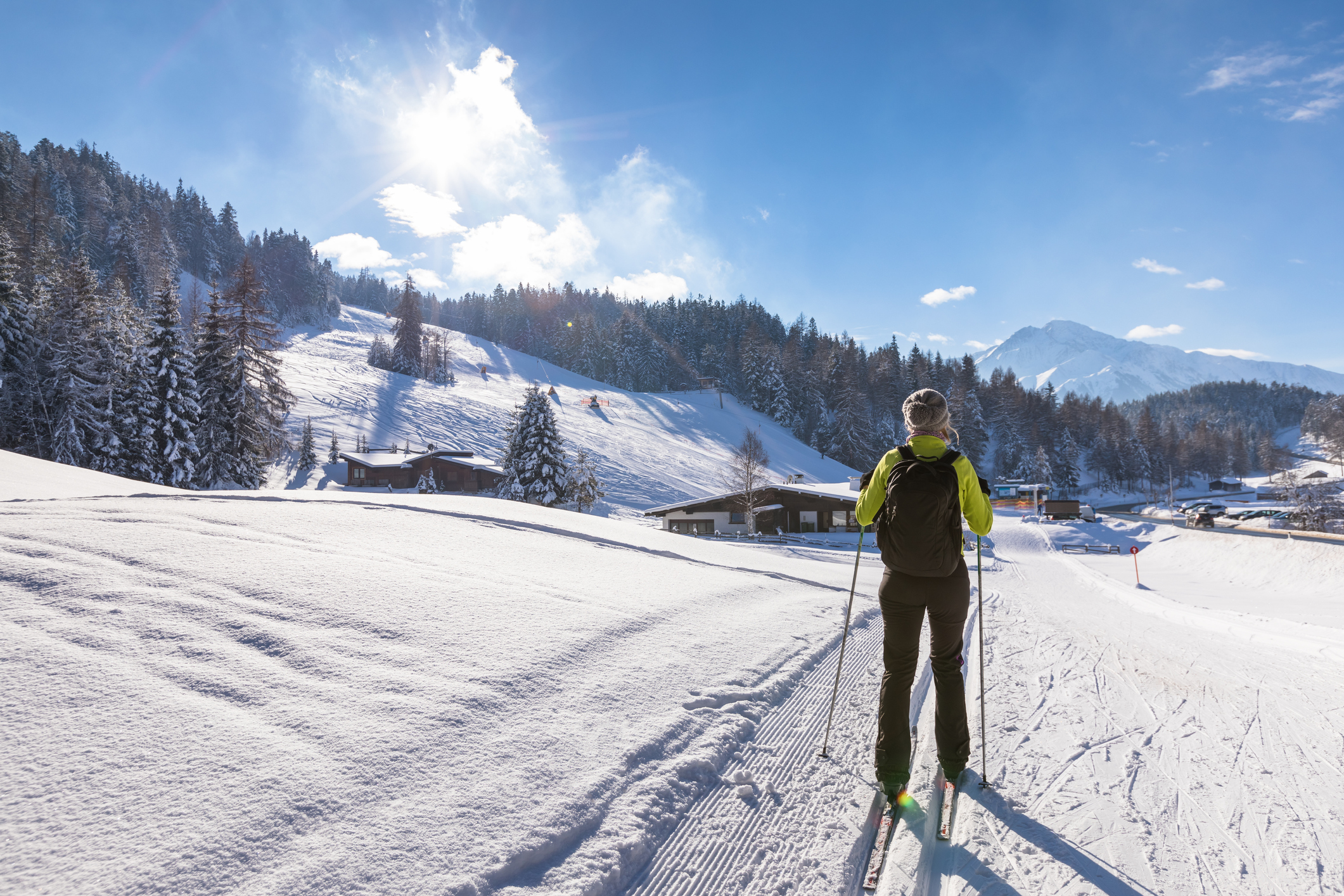 Langläuferin vor einer atemberaubenden Kulisse aus tiefverschneiten Bergen und Wäldern