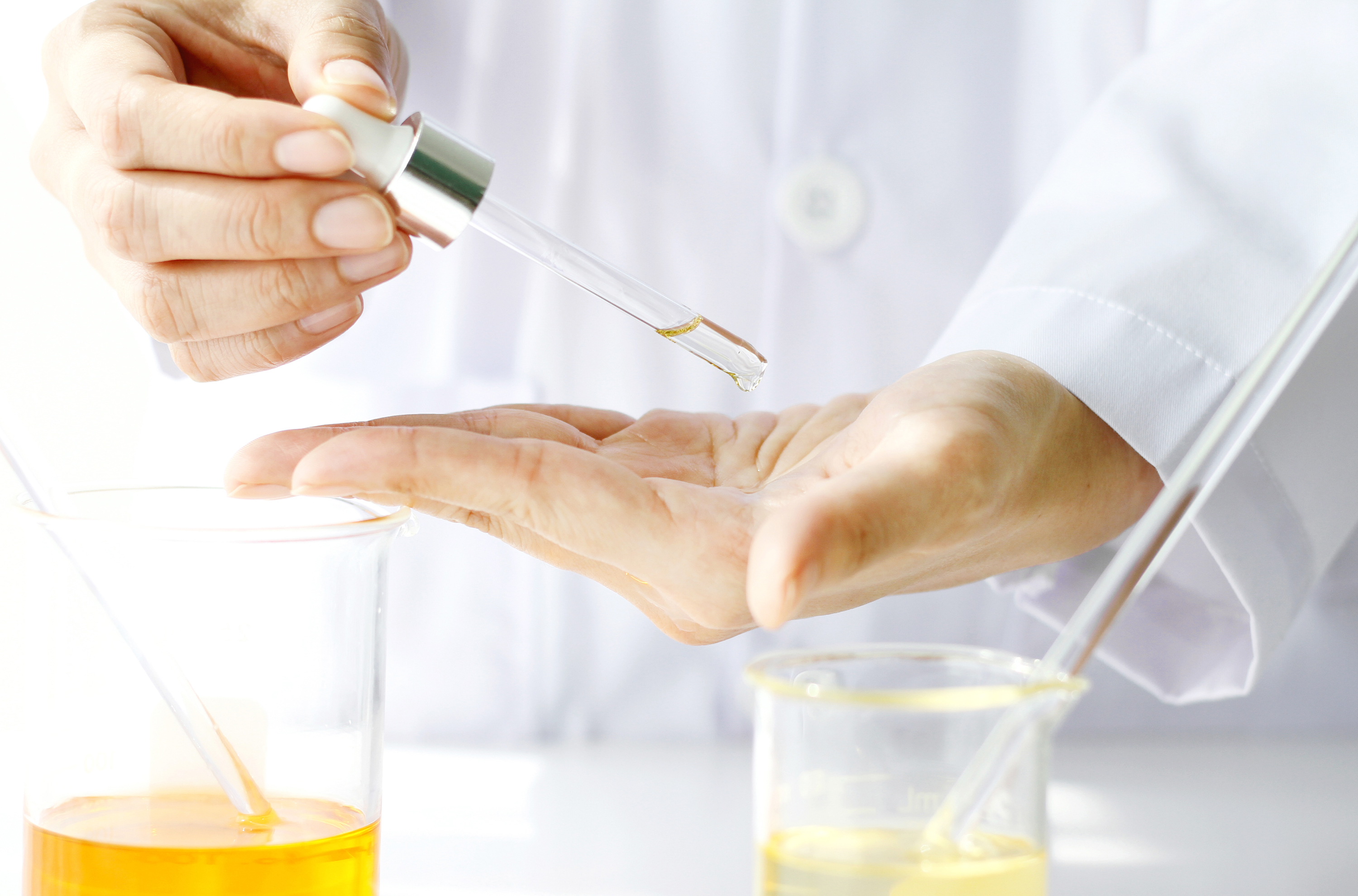 Bildausschnitt, Hände eines Mannes im Laborkittel plus Laborgefäße