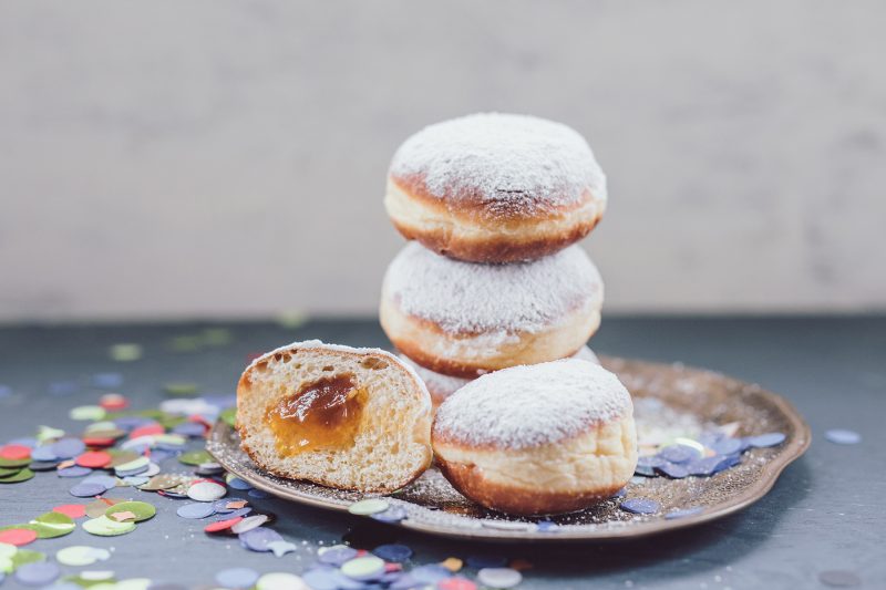 Aufgetürmte Krapfen, ein aufgeschnittener Krapfen mit Marmelade, Konfetti