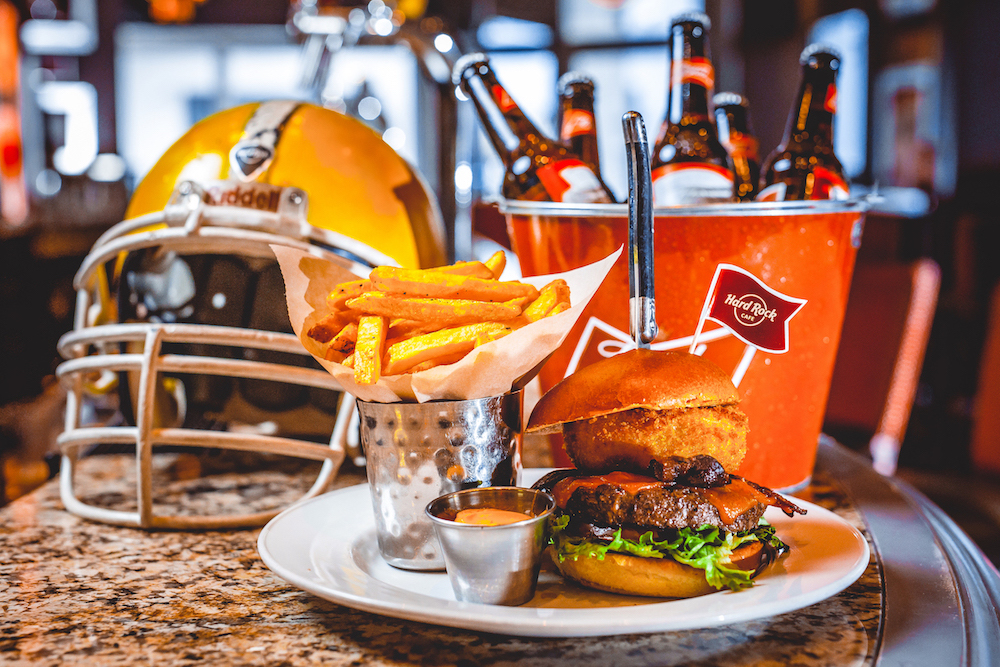 Ein Football-Helm, ein Burger mit Pommes und ein Kühler mit Bierflaschen