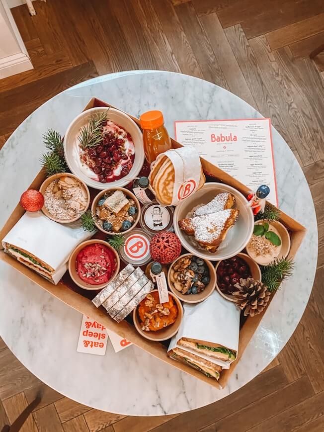 Tisch mit Karton, darin Sandwiches, Pancakes uvm