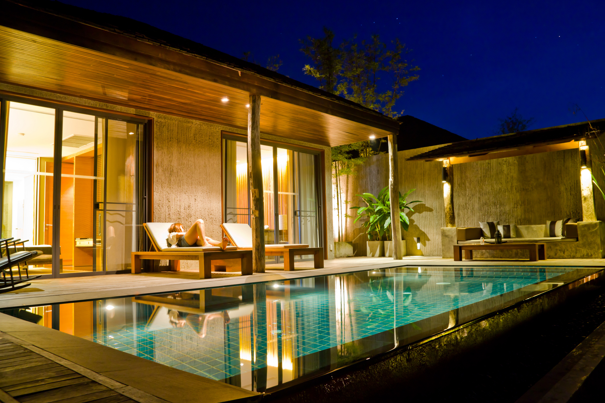 Ein hell erleuchteter Swimmingpool im Garten eines modernen Hauses bei Nacht