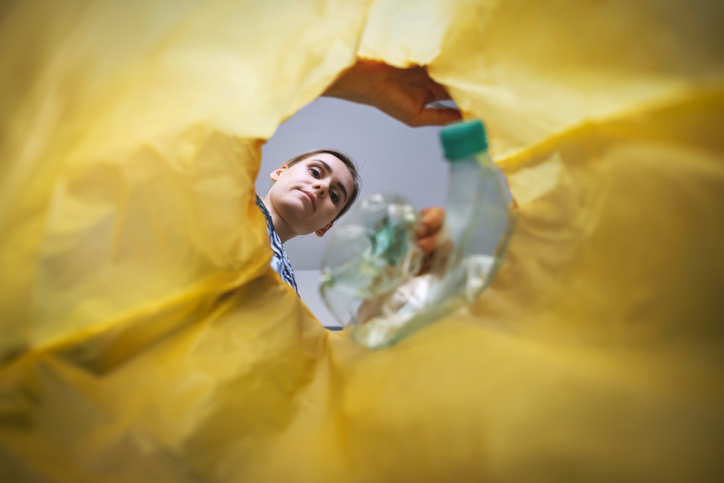 Frau entsorgt Plastik im Müllsack