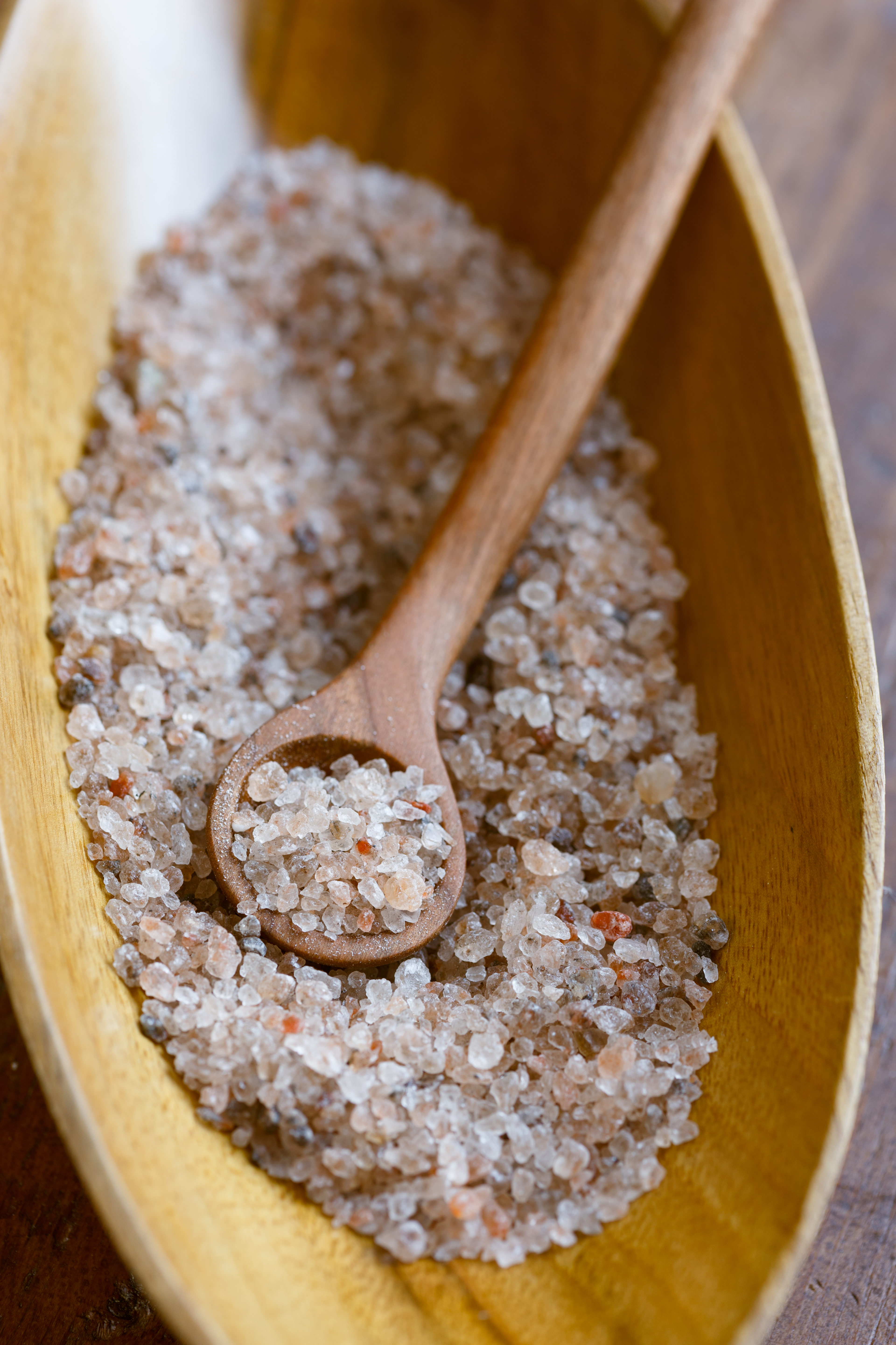 Eine Holzschale aus der ein Löffel voll Bergkernsalz geschöpft wird