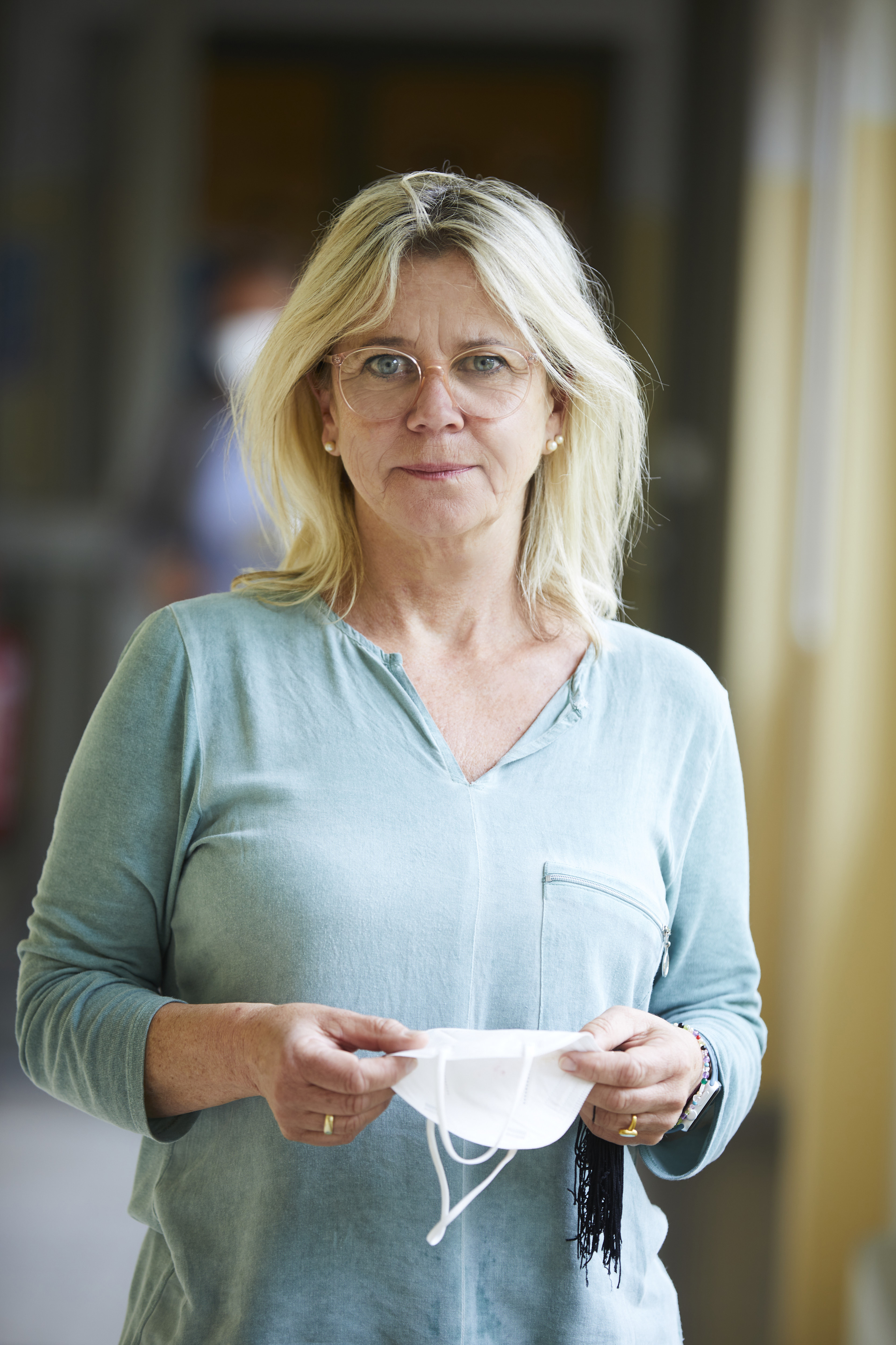 Porträt von Petra Erian, die eine FFP2-Schutzmaske in Händen hält