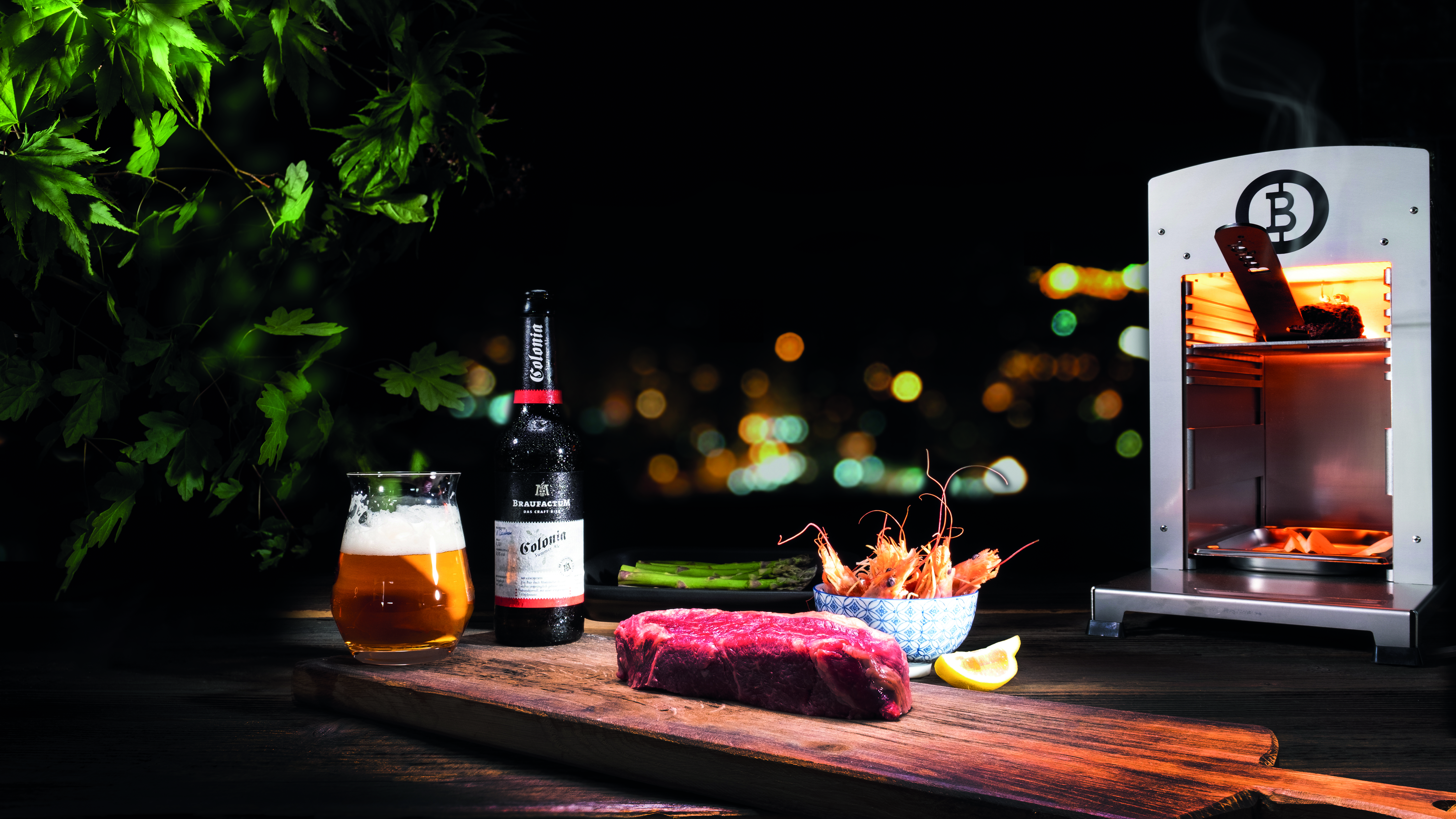 Ein Beefer-Hochleistungsofen hinter einem Glas Bier und einem rohen Steak auf einem Gartentisch