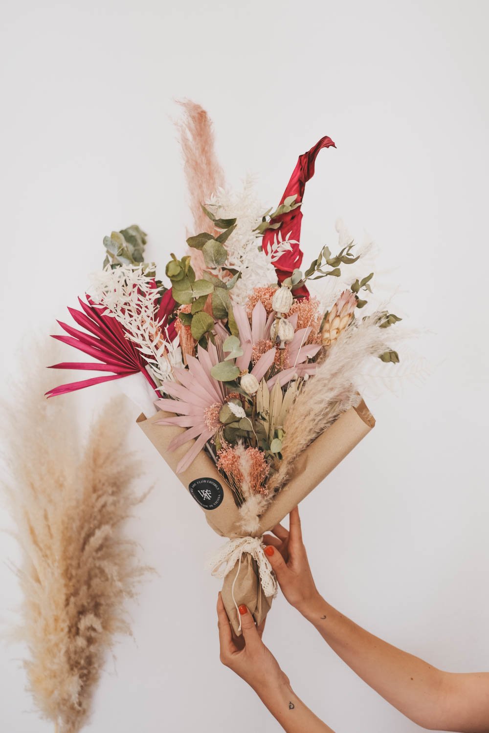 Eine Hand hält einen Strauß mit getrockneten Blumen und Gräsern