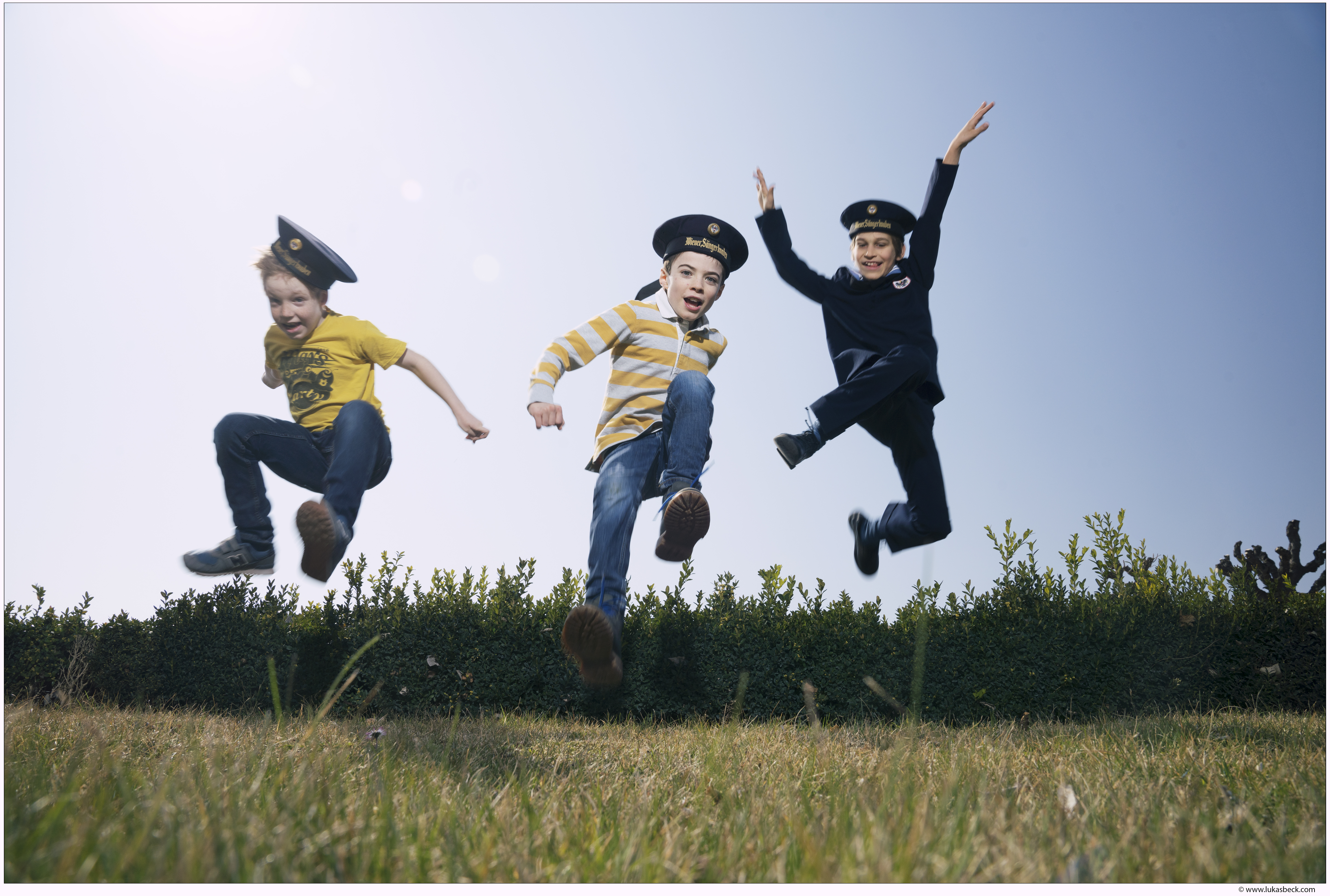 Drei Wiener Sängerknaben springem durch eine Wiese